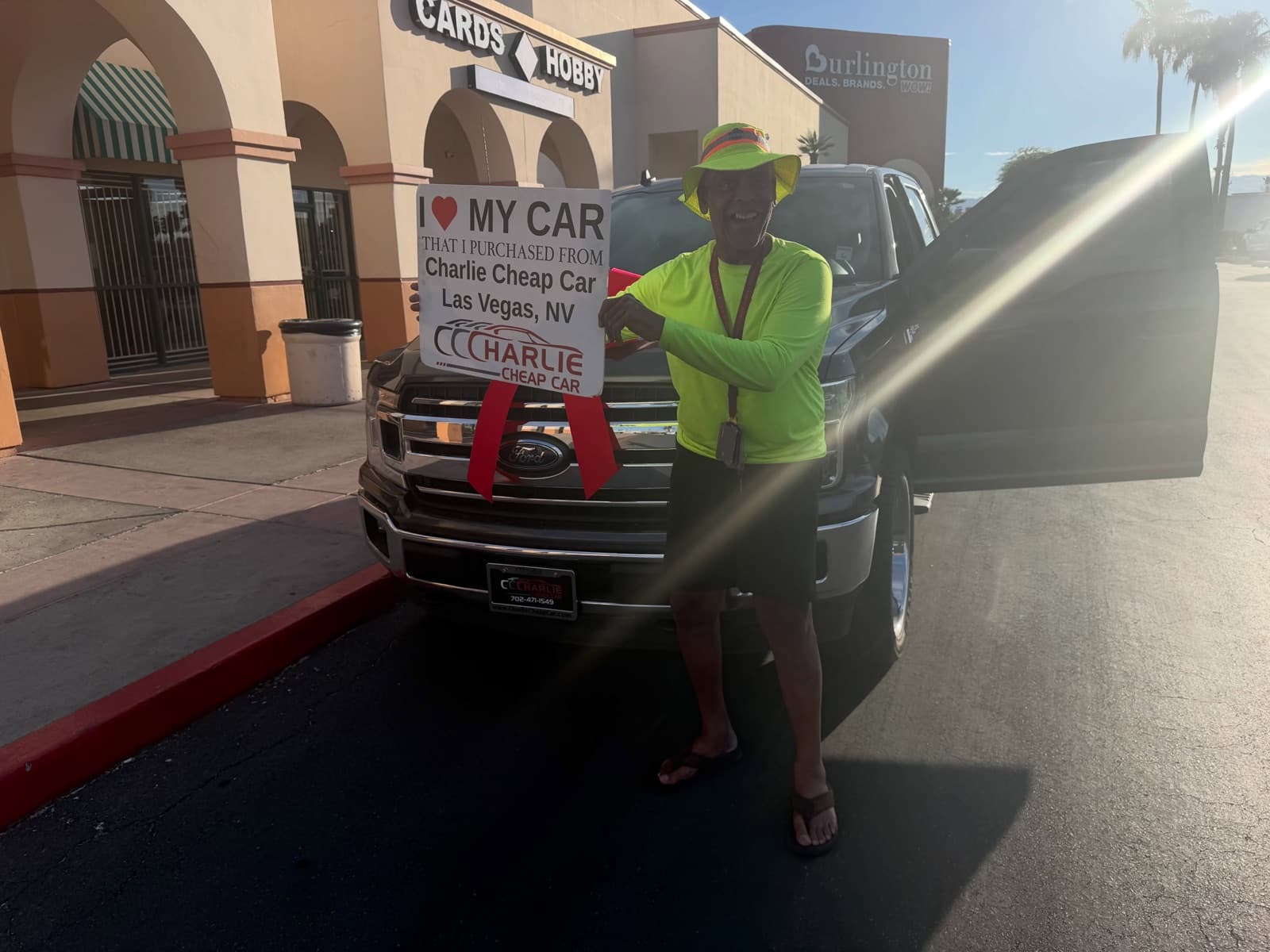 Customer holds an I love my car sign beside a black Ford F-150 pickup truck